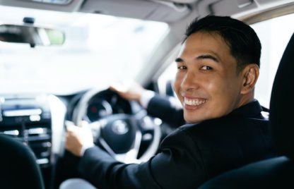 Asian businessman driving car and smile, car insurance concept.