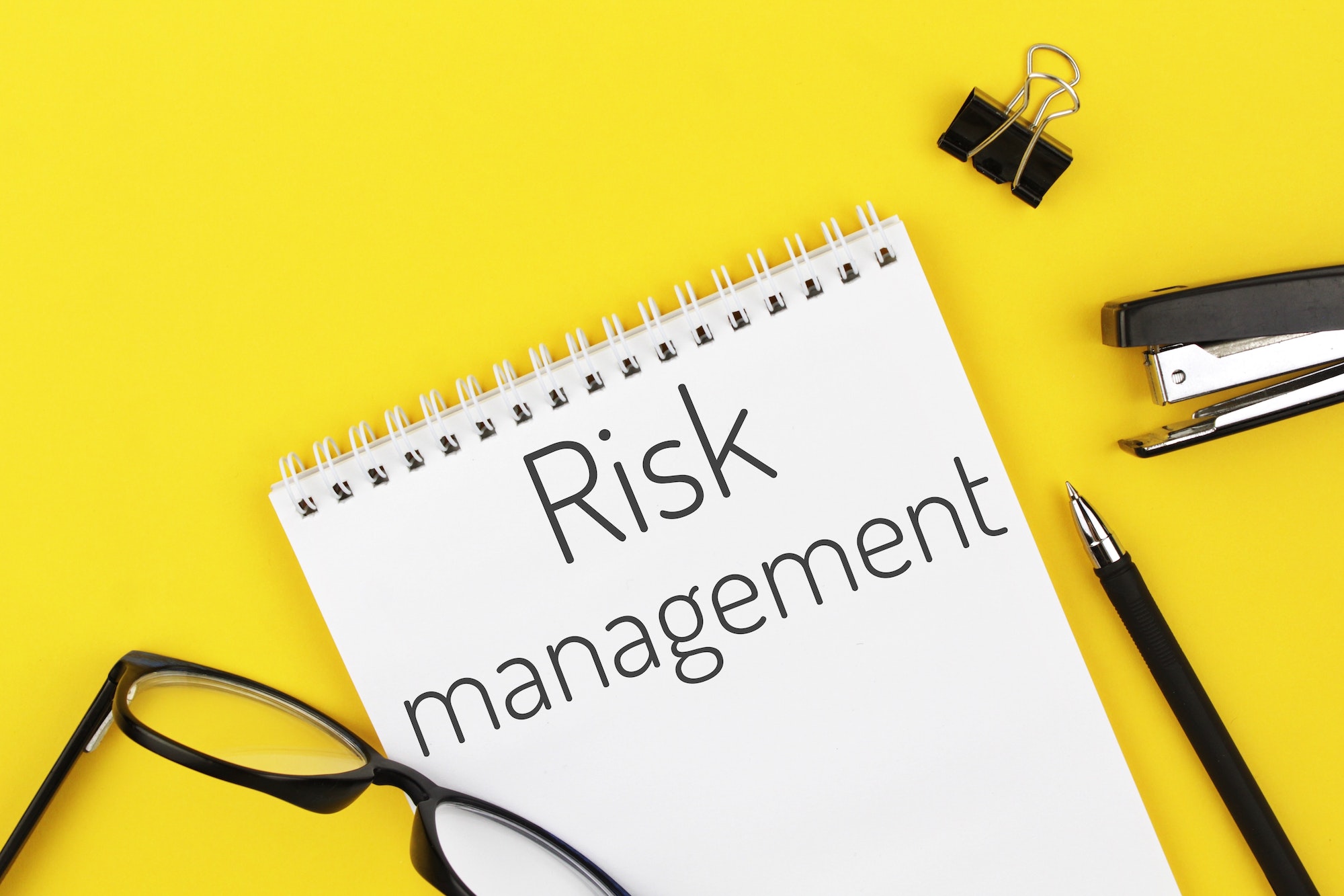 notebook with word risk management on a yellow background