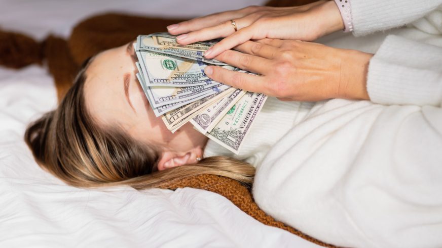 Woman holding cash money near face. smelling dollars