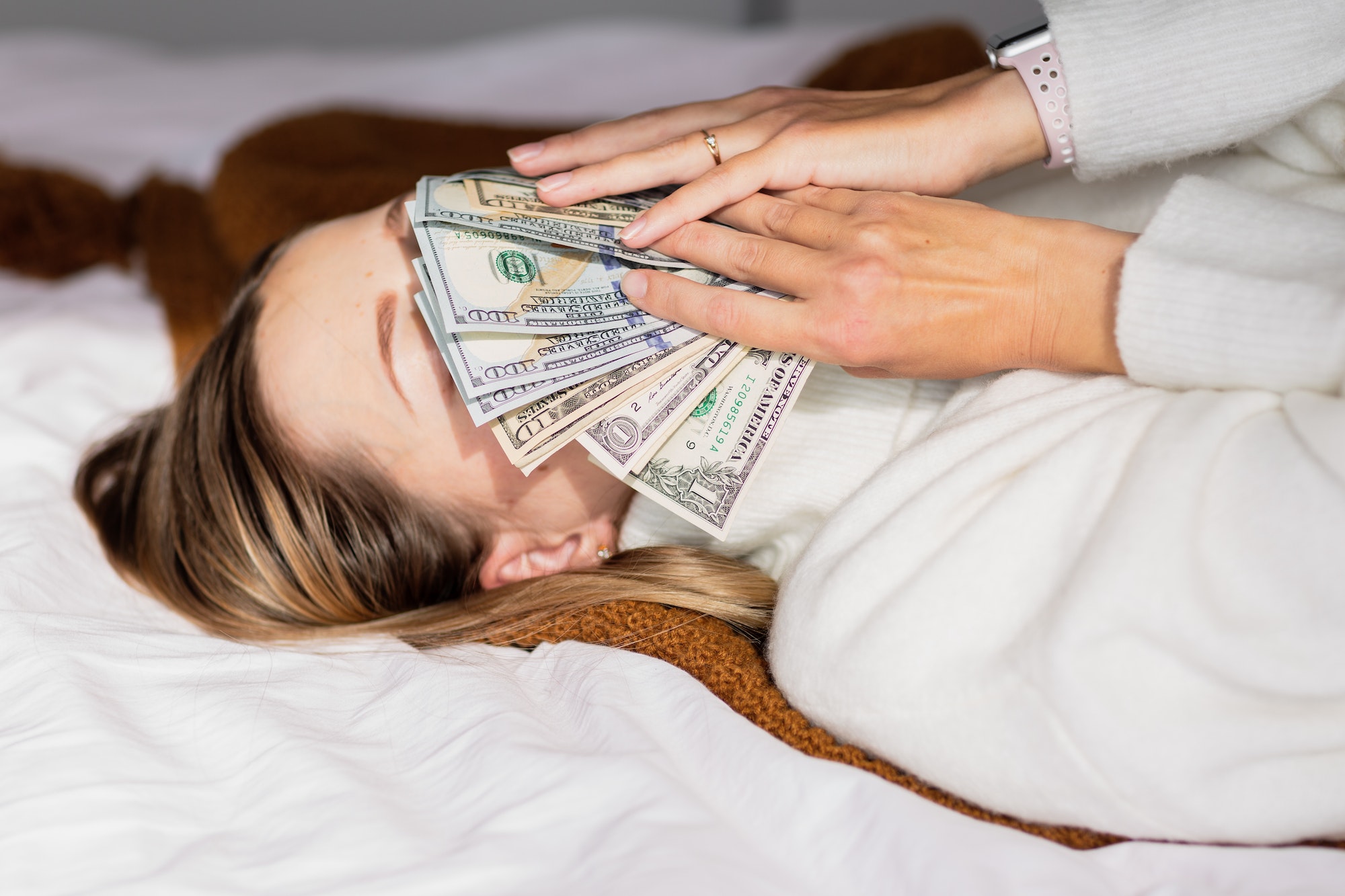 Woman holding cash money near face. smelling dollars