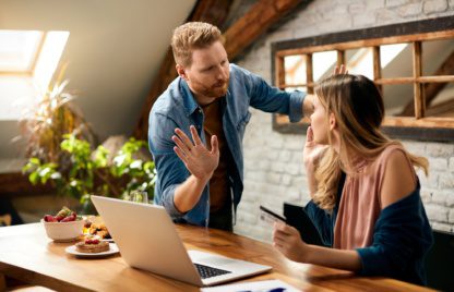 Young couple arguing about debt on their credit card while shopping online at home.