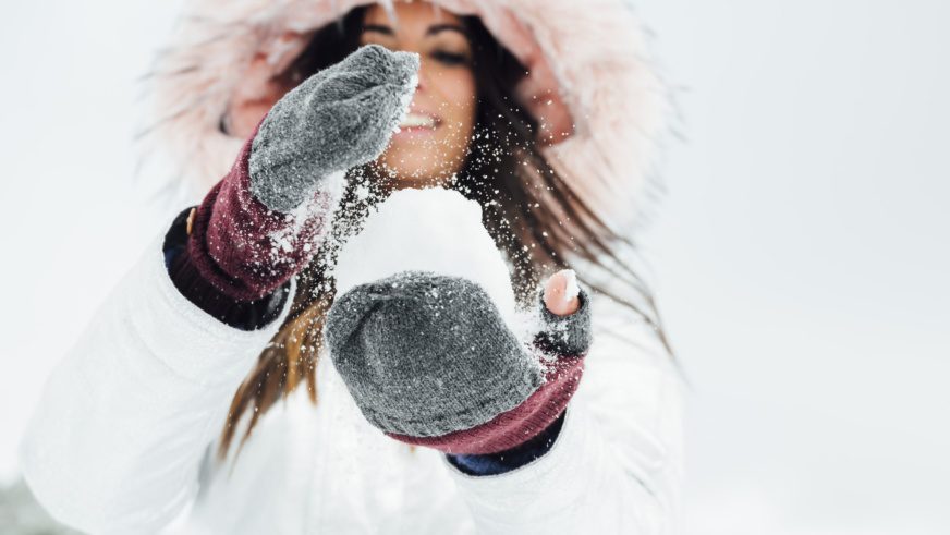 Young woman playing with snowball